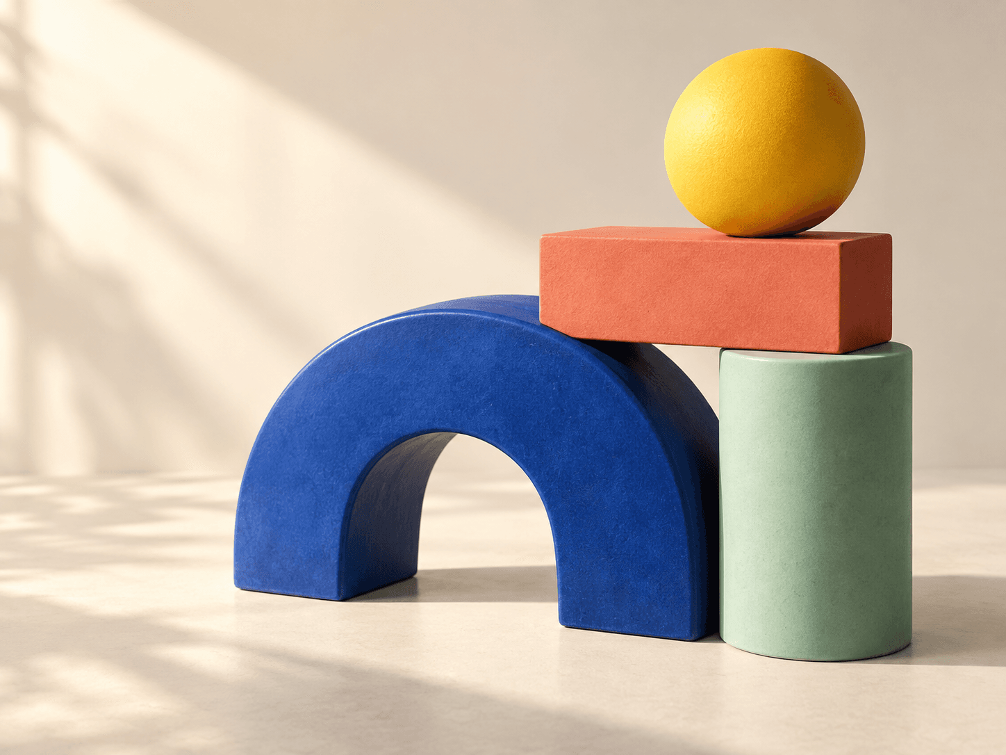A cobalt arch, mint cylinder, coral block, and golden sphere arranged together